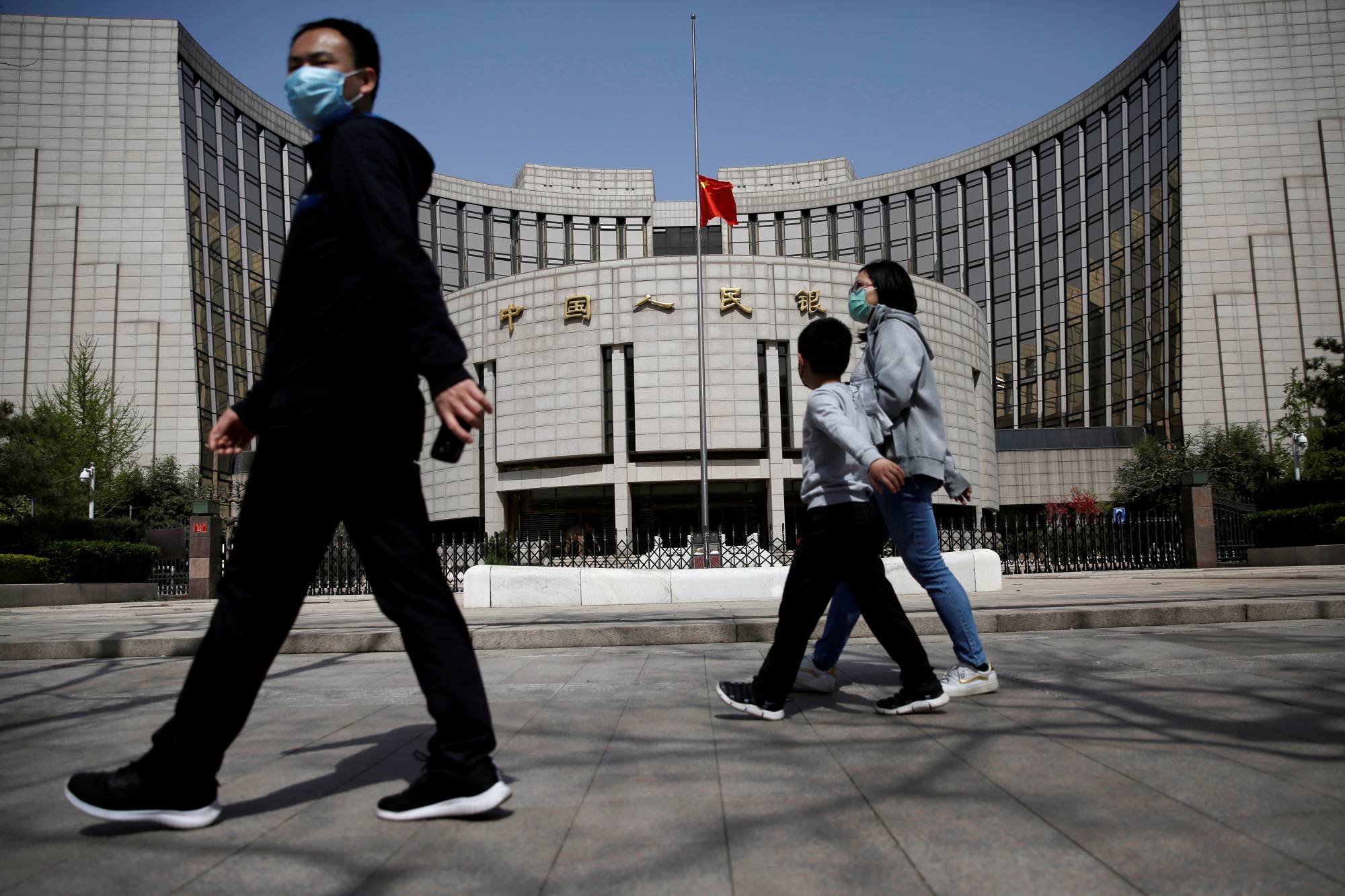 People walk past the headquarters of the People's Bank of China in early April. Just since the past month, worried savers in China have descended on three banks to withdraw funds amid rumors of cash shortages that were later dismissed as false. | REUTERS