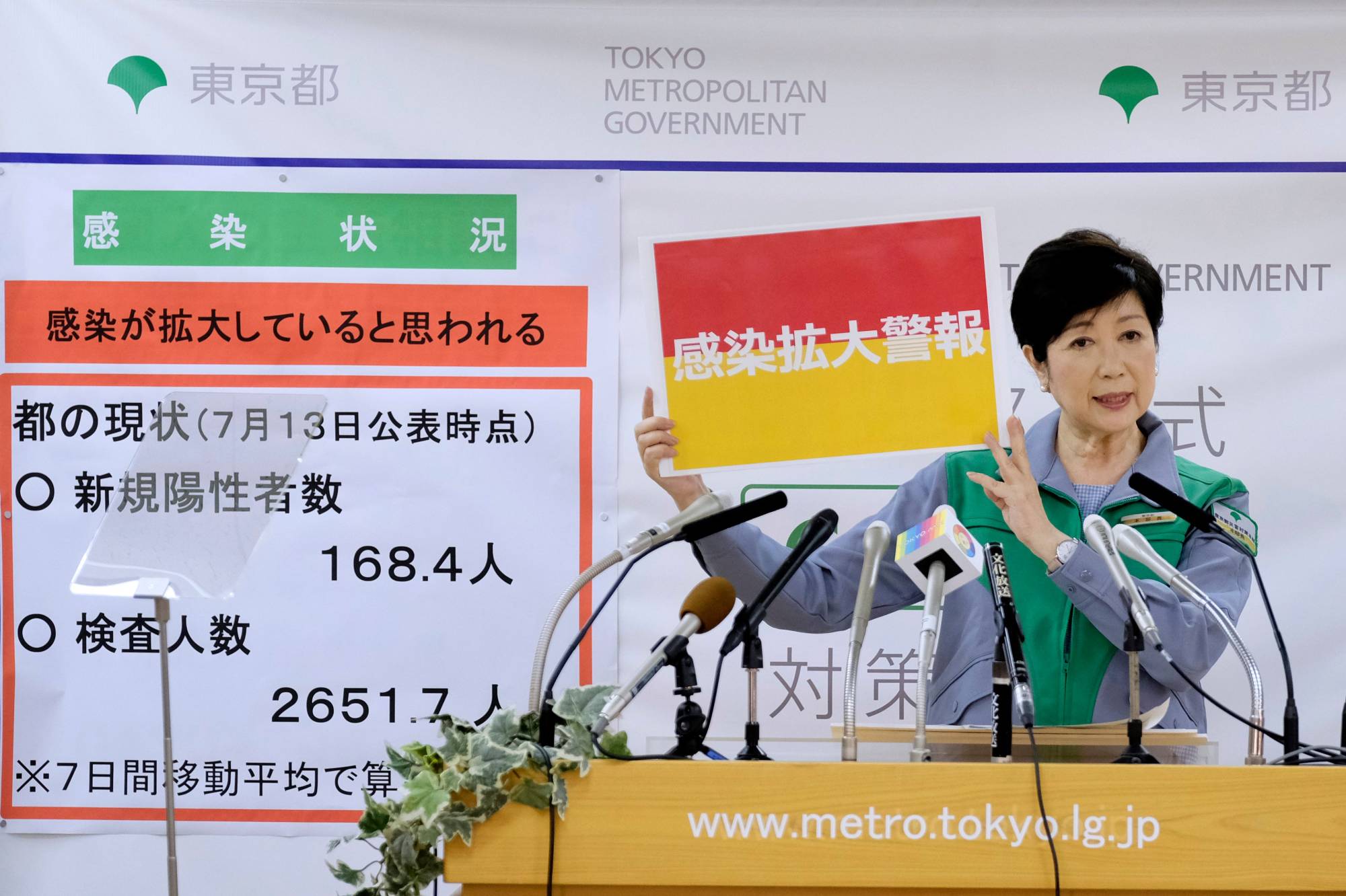 Tokyo Gov. Yuriko Koike displays a sign reading 'Infection spread alert' as she speaks during a news conference Wednesday. | AFP-JIJI