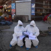 Health care workers organize their documents after house-to-house testing for the new coronavirus in El Alto, Bolivia, on Saturday. | AP