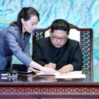 North Korean leader Kim Jong Un is assisted by his sister, Kim Yo Jong, as he signs documents at the truce village of Panmunjom, South Korea, inside the Demilitarized Zone separating the two Koreas in April 2018.    | KOREA SUMMIT PRESS POOL / VIA REUTERS