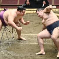 Yokozuna Kakuryu falls during his bout against maegashira Endo on Sunday at Ryogoku Kokugikan. | KYODO