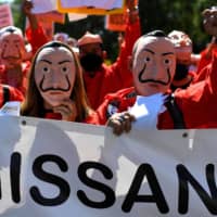 Nissan employees, wearing the red jumpsuit and Dali mask of the Spanish Netflix hit series La Casa de Papel (Money Heist), shout slogans during a demonstration in Madrid, last week against the closure of the carmaker\'s factory of Barcelona.
 | AFP-JIJI