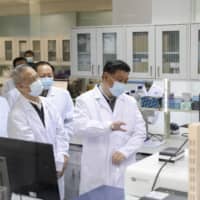 Chinese leader Xi Jinping learns about progress on the research into COVID-19 vaccine candidates during a visit to the Academy of Military Medical Sciences in Beijing in March. | XINHUA / VIA AP