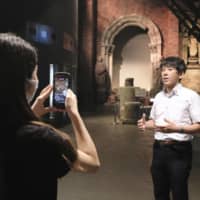 Hibiki Yamaguchi (right) gives an online tour of the Nagasaki Atomic Bomb Museum on Friday. | KYODO