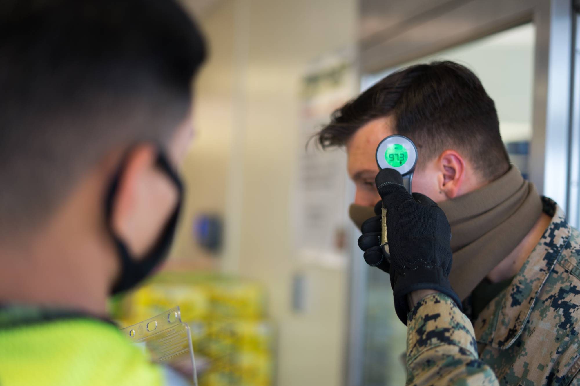 A U.S. Marine conducts a temperature check at the front of the commissary at Camp Courtney in Okinawa Prefecture on July 13. | U.S. MARINE CORPS
