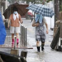 People walk in heavy rain in the Kumamoto Prefecture city of Hitoyoshi on Friday. | KYODO