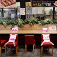 Social distancing signs tell shoppers where they shouldn\'t sit in a dining area in an Aeon shopping mall in Chiba on May 28. | REUTERS