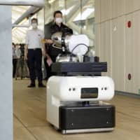 A cleaning robot sprays disinfectant at Takanawa Gateway Station in Tokyo on Monday. | KYODO