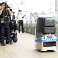A robot carries luggage at Takanawa Gateway Station in Tokyo on Monday. | KYODO