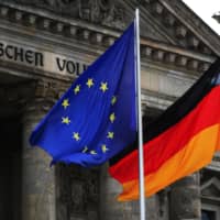 The German national and European Union flags fly outside the Reichstag building on July 1. Germany can no longer rely on its famed parsimony for propping up the value of bunds. | BLOOMBERG