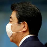 The government is pushing ahead with the distribution of its much derided \"Abenomasks,\" even though commercially made masks are now readily available, prompting a renewed outcry on social media. | POOL / VIA REUTERS