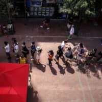 People line up at a polling station to vote outside MTR Corp.\'s Whampoa Station during an unofficial primary election, organized by pro-democracy opposition parties to select favored candidates for the legislative election, in Hong Kong, on July 11. | BLOOMBERG