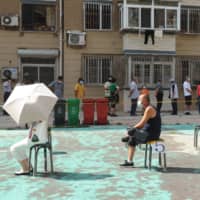 People sit on socially distanced chairs as they wait to undergo COVID-19 tests at a makeshift testing center in Dalian, China, on Tuesday.  | AFP-JIJI