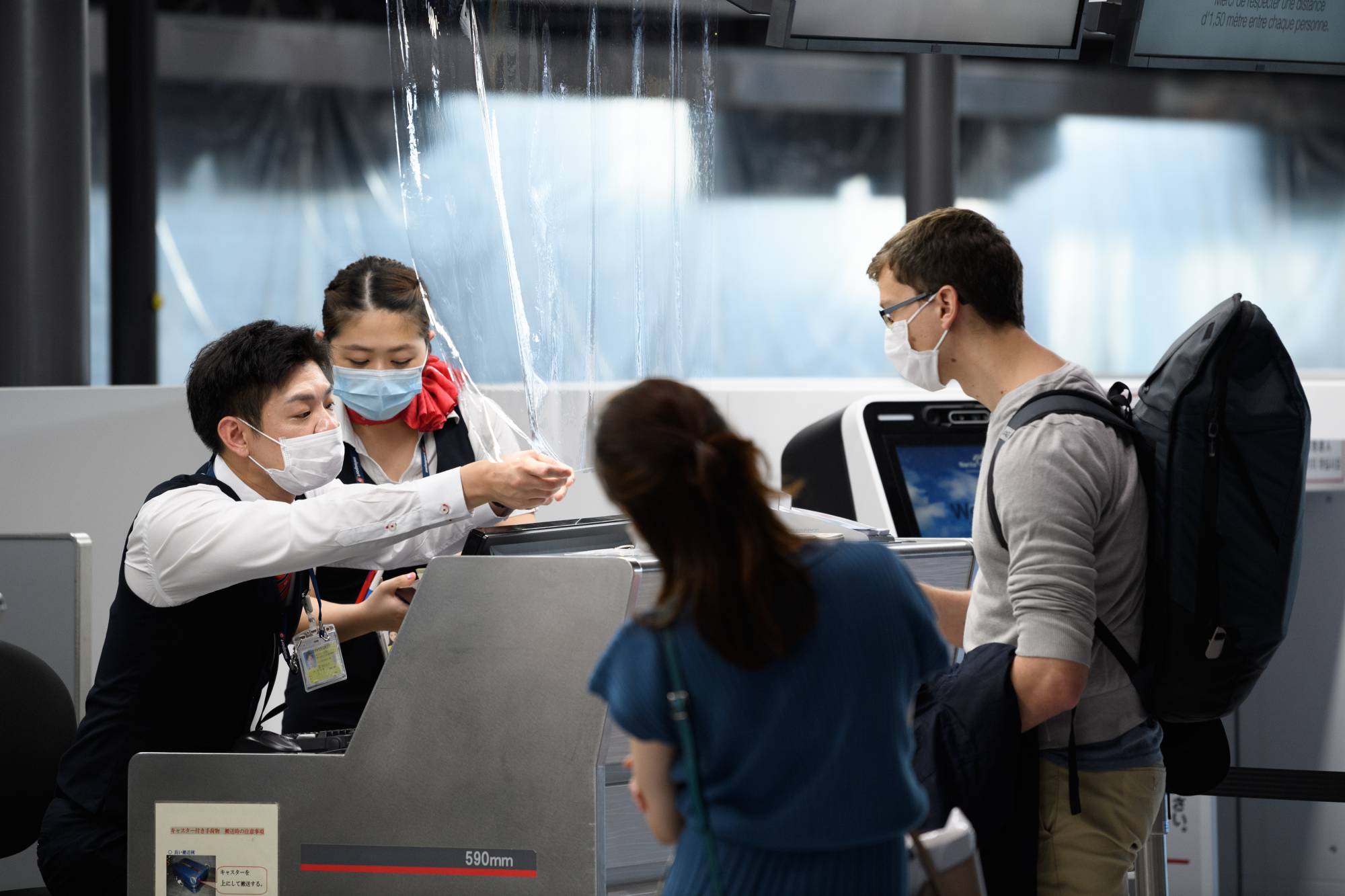 Employees assist passengers at the Air France-KLM Group check-in desk inside Narita Airport in Chiba Prefecture on July 19. | BLOOMBERG