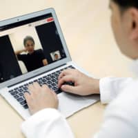 A doctor demonstrates a telemedicine application in Tokyo on July 8. A \"shock therapy\" policy is needed to overcome vested interests and push Japan\'s digital transformation forward. | REUTERS
