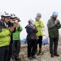 The kin of those killed in the September 2014 eruption of Mount Ontake offer prayers at Otaki Peak on Friday after entry restrictions were lifted for the first time since the disaster. | KYODO