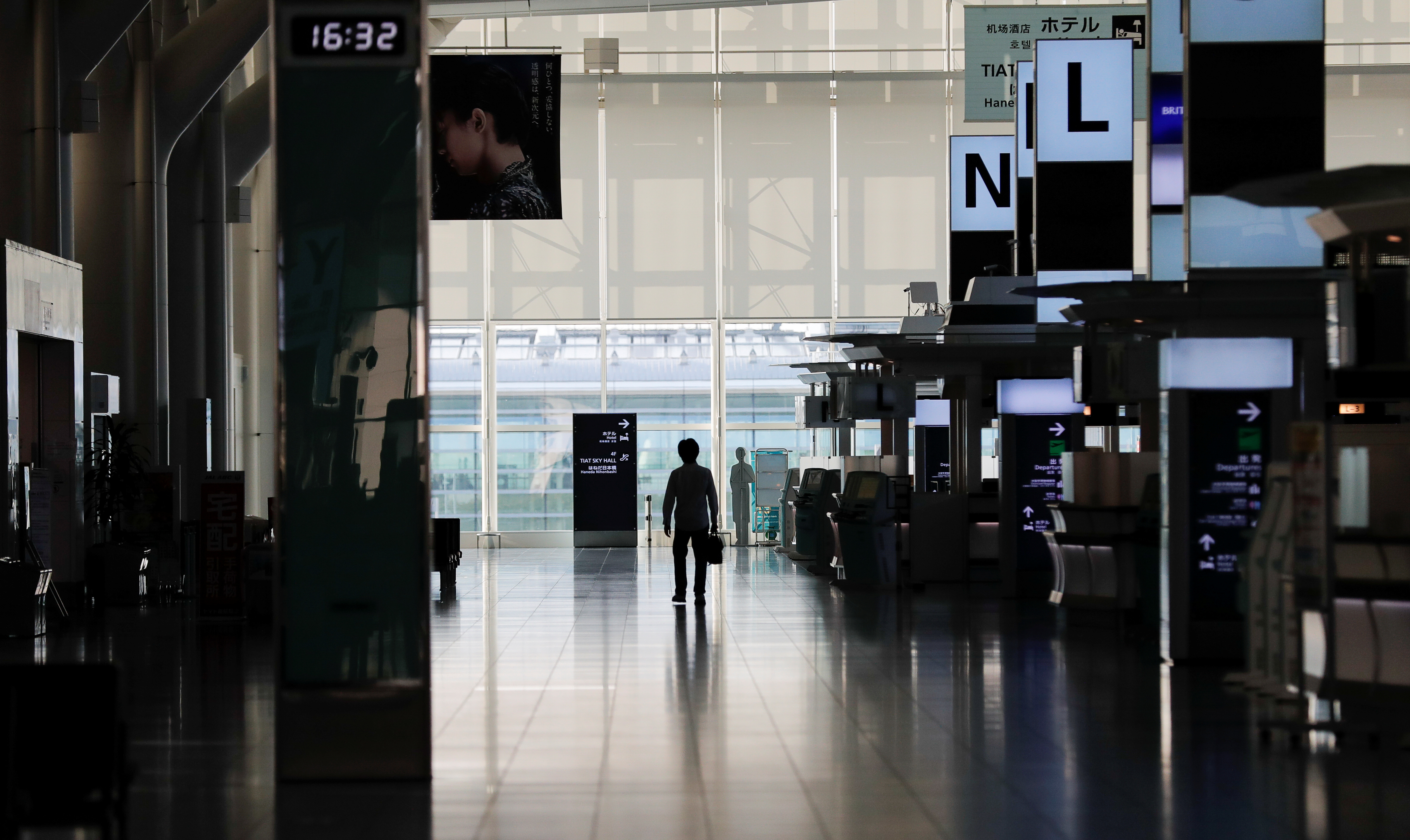 A person stands in an almost empty terminal of Tokyo's Haneda Airport in late April. Starting Tuesday, Japan is set to lift its entry restrictions on foreign residents, allowing those who left before the strict coronavirus curbs were imposed to return, and those planning to leave temporarily to proceed without fear of being locked out. | REUTERS