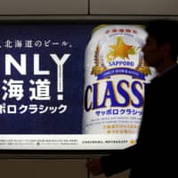 A man walks past an Sapporo Beer advertising board at New Chitose Airport Station in Hokkaido in 2016. | REUTERS