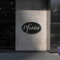 A pedestrian walks past Pfizer Inc. headquarters on July 22 in New York City. | GETTY IMAGES / VIA KYODO