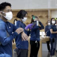 Employees prepare to reopen an Apple store in Tokyo\'s Omotesando district on June 3. | BLOOMBERG