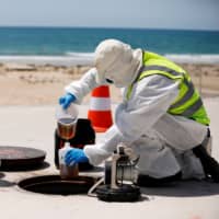 Employees of a wastewater management technology firm demonstrate sewer surveillance, which aims to pinpoint unknown COVID-19 outbreaks, in Ashkelon, southern Israel. | REUTERS 