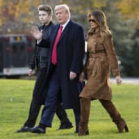 U.S. President Donald, first lady Melania Trump, and their son, Barron, walk to board Marine One on the South Lawn of the White House in Washington last November. | AP