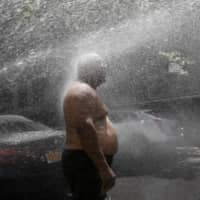 A man cools off in the spray from a fire hydrant Tuesday in New York. | AP