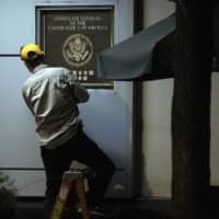 A worker removes a plaque from the shuttered United States Consulate in Chengdu, China, on Wednesday. Rancor between the world\'s top two economies has spread from a trade war to include Hong Kong, Chinese Muslims, spying accusations and control of the South China Sea. | AP