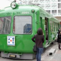 An old train car, nicknamed \"green frog,\" served as a tourist information center outside Tokyo\'s Shibuya Station. | KYODO