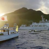 A Chinese vessel (right) sails near the Senkaku Islands in 2013. | KYODO