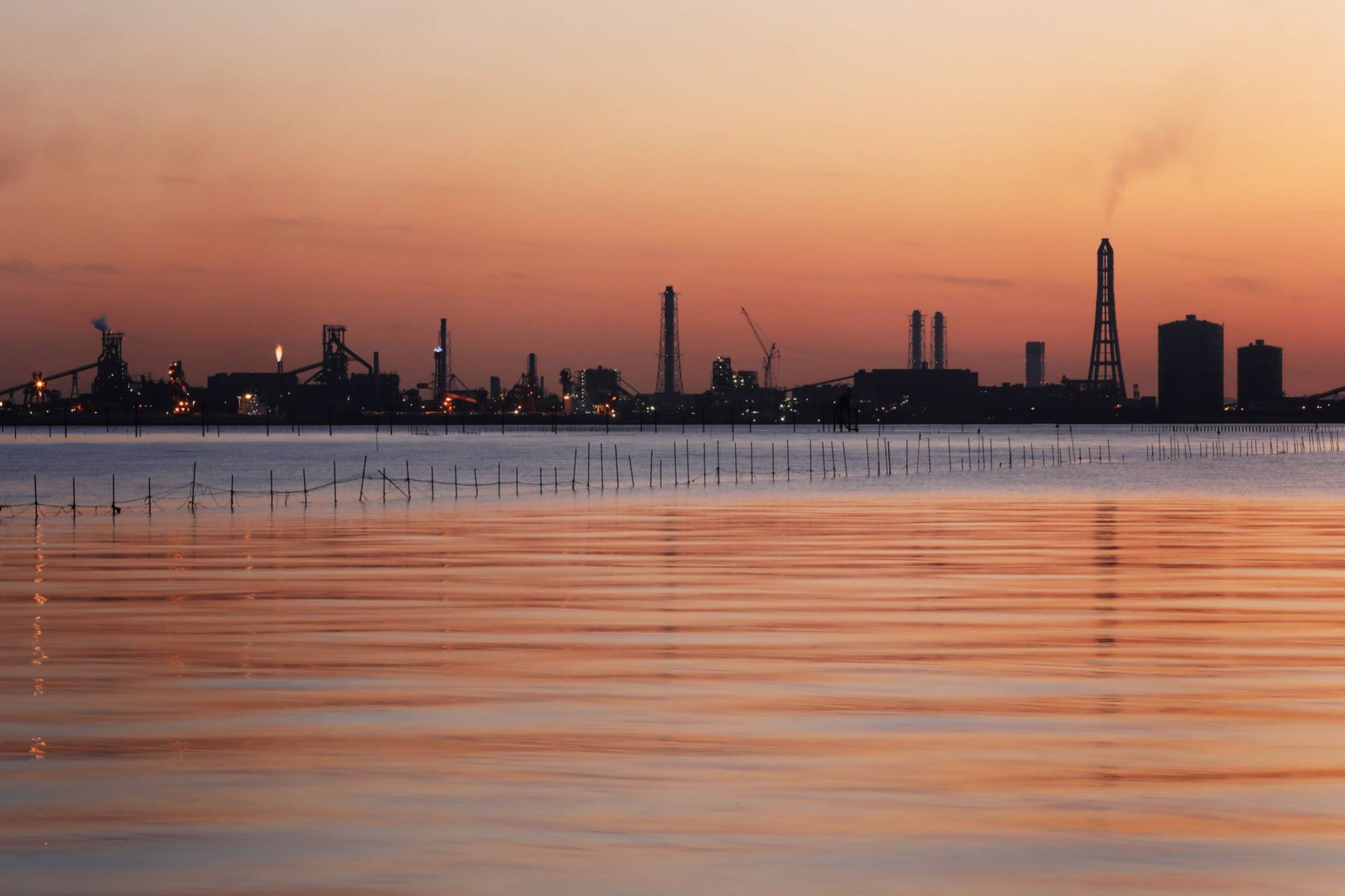 A Nippon Steel & Sumitomo Metal Corp. plant stands illuminated at dusk in Kimitsu, Chiba Prefecture. | BLOOMBERG