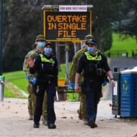 Police officers and soldiers patrol a popular running track in Melbourne on Tuesday after the state announced new restrictions as the city battles fresh outbreaks of the COVID-19 coronavirus.  | AFP-JIJI