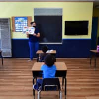 A teacher reads to a pre-school class of children who are wearing masks and with desks spaced apart as per coronavirus guidelines during the summer school session in Monterey Park, California, on July 9.  U.N. Secretary-General Antonio Guterres warned on Tuesday that the world faces a \"catastrophe\" due to school closures caused by the COVID-19 pandemic. | AFP-JIJI