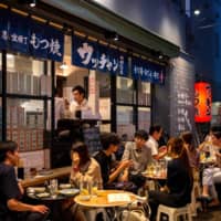 People sit in an alley of restaurants and bars in Tokyo\'s Shimbashi district on Friday. An analysis by the WHO of 6 million infections between Feb. 24 and July 12 found that the share of people aged 15-24 years rose to 15 percent from 4.5 percent. | AFP-JIJI