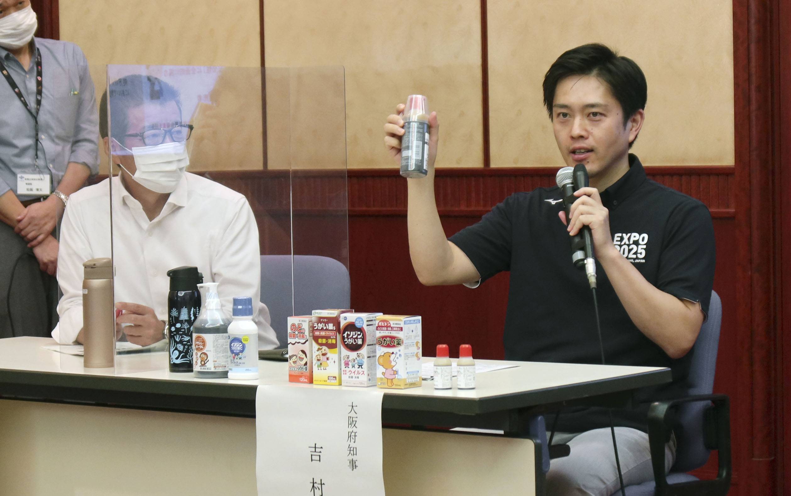 Osaka Gov. Hirofumi Yoshimura (right) shows a gargle medicine at a news conference in Osaka Tuesday, as Osaka Mayor Ichiro Matsui looks on. | KYODO