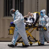 Medics transfer a patient on a stretcher from an ambulance outside of a hospital near Miami.  | AFP-JIJI