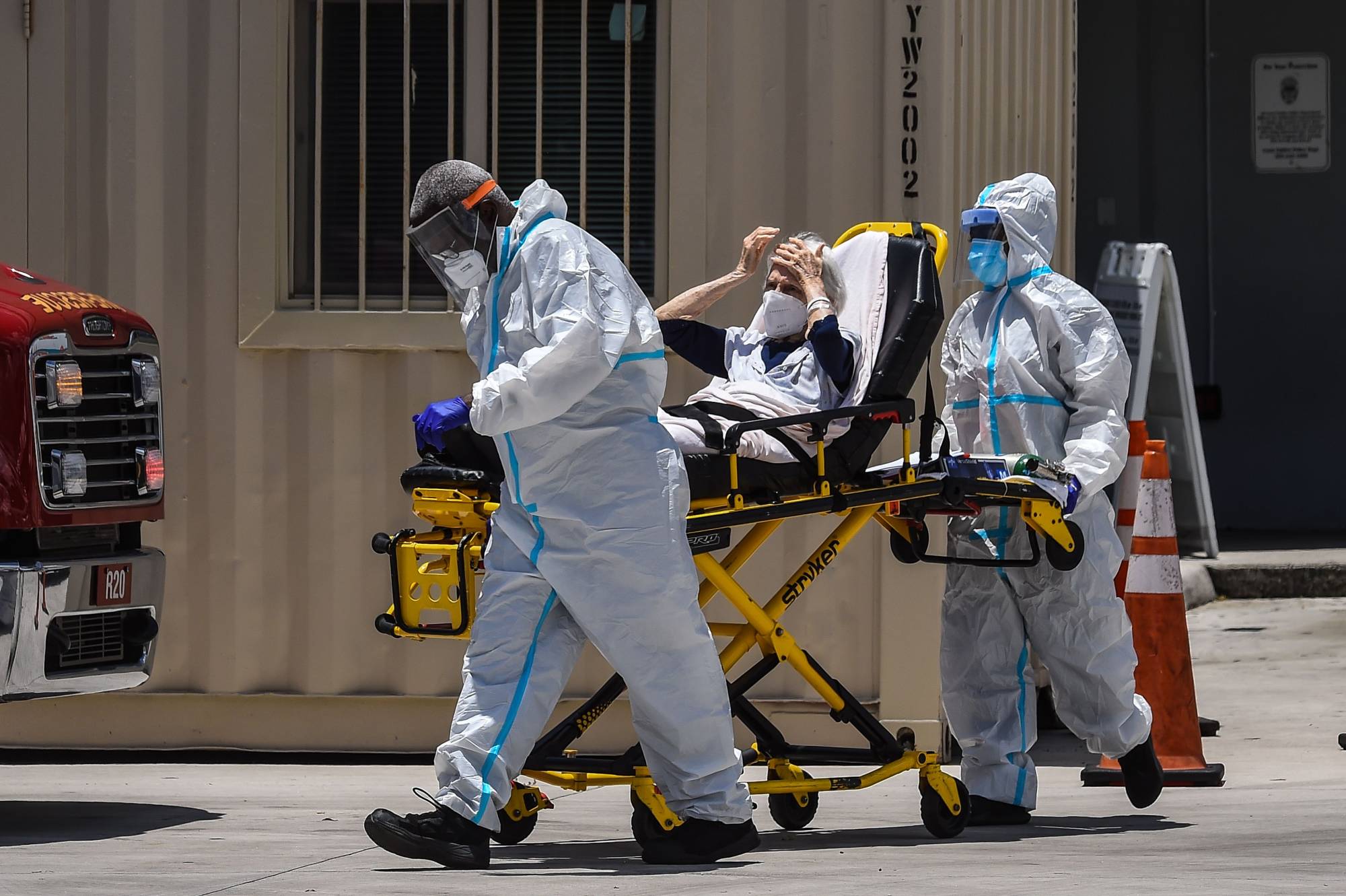 Medics transfer a patient on a stretcher from an ambulance outside of a hospital near Miami. | AFP-JIJI