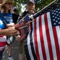 Protestors hand out American flags outside of the Ohio Statehouse during a right-wing protest against mask-wearing last month in Columbus.  | AFP-JIJI