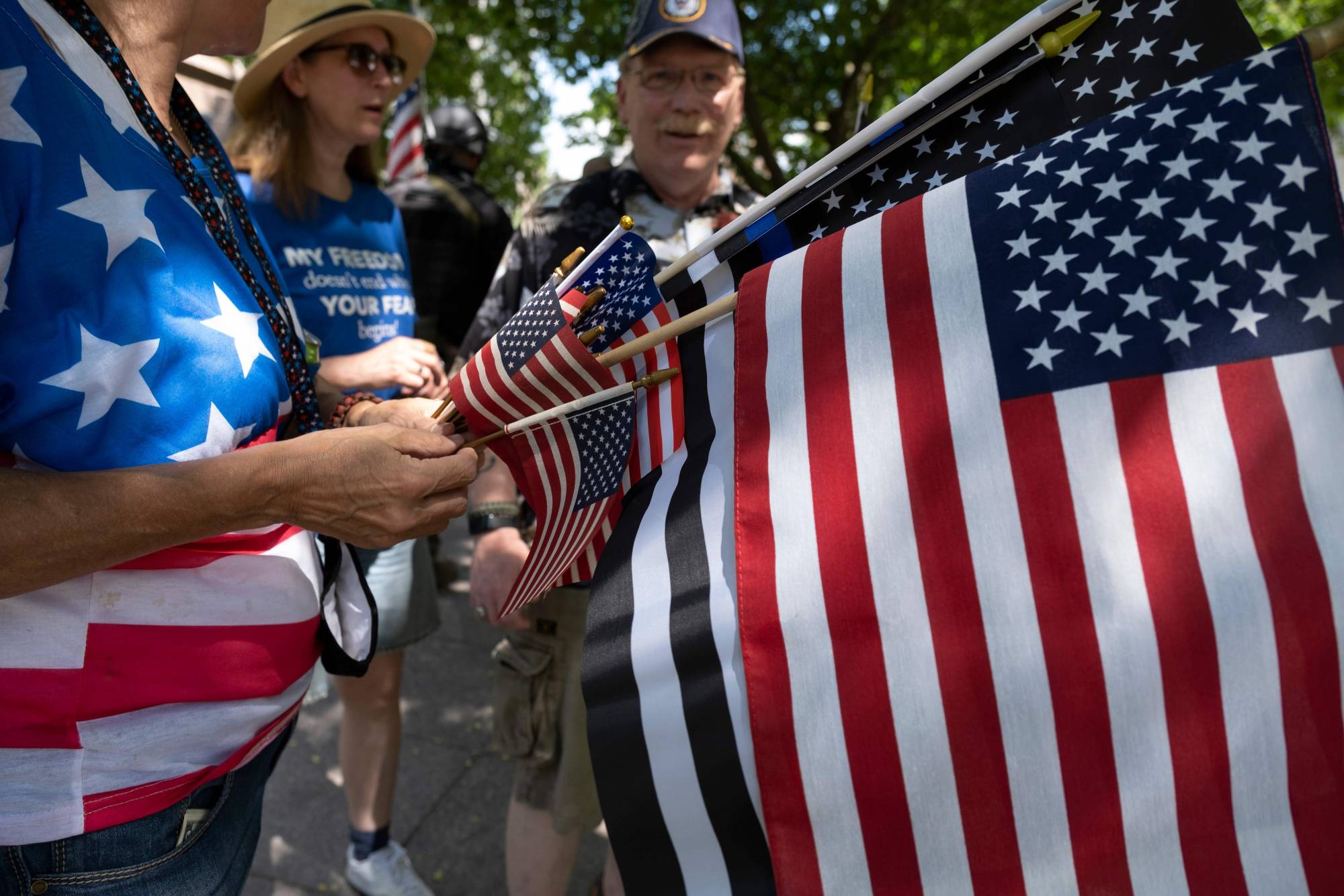 Protestors hand out American flags outside of the Ohio Statehouse during a right-wing protest against mask-wearing last month in Columbus. | AFP-JIJI