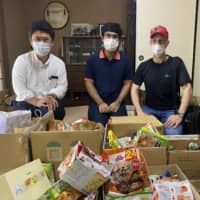 Dinner donations: Wataru Ogura, Trishit Banerjee and Justin Velgus display some of the donations that will go to needy people from the Sendai Food Bank. | COURTESY OF TRISHIT BANERJEE
