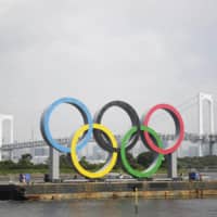 The Olympic rings are pulled out of Tokyo Bay by a barge on Thursday. The monument is being taken away for safety inspections. | AP