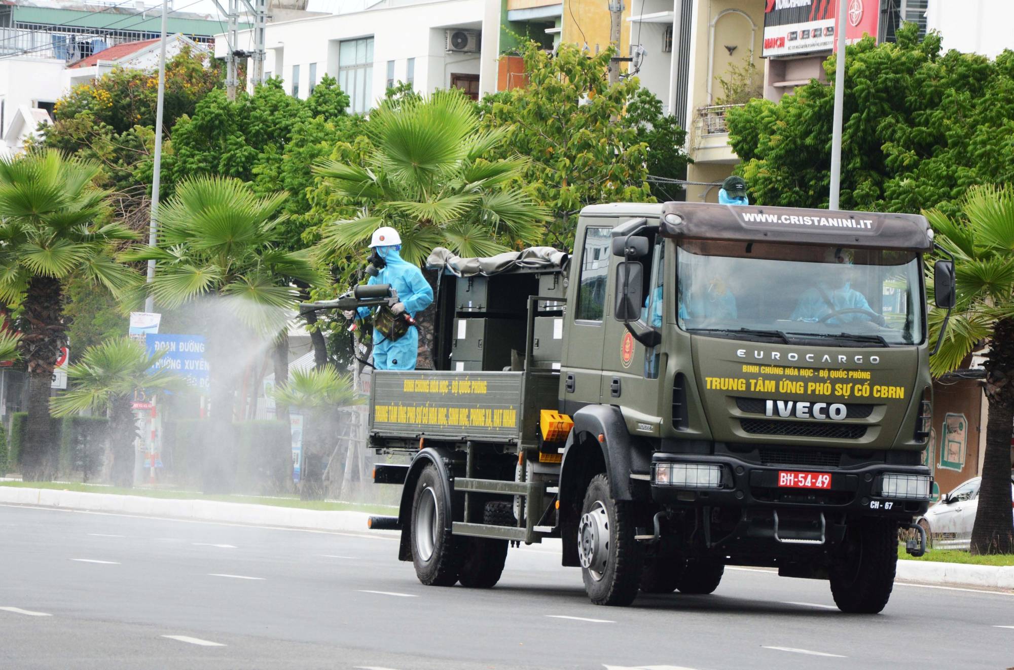 A soldier sprays disinfectants on a road from a military vehicle to help curb a coronavirus outbreak in Da Nang, Vietnam, on Aug. 3. | REUTERS