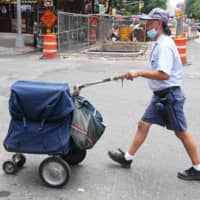 A U.S. Postal Service worker walks with his cart in New York City.  | REUTERS 