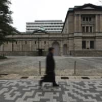 A pedestrian walks past the Bank of Japan headquarters in Tokyo. | BLOOMBERG