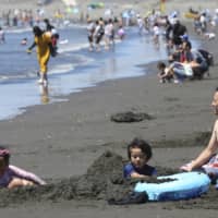 People cool off at Shonan Beach amid scorching summer heat in Fujisawa, Kanagawa Prefecture, on Tuesday. | AP