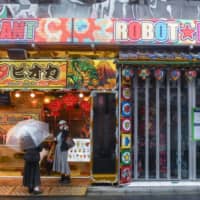 Customers stand in front of a bubble tea shop next to the Robot Restaurant, temporarily closed due to the coronavirus, in the Shinjuku district of Tokyo on April 1. | BLOOMBERG