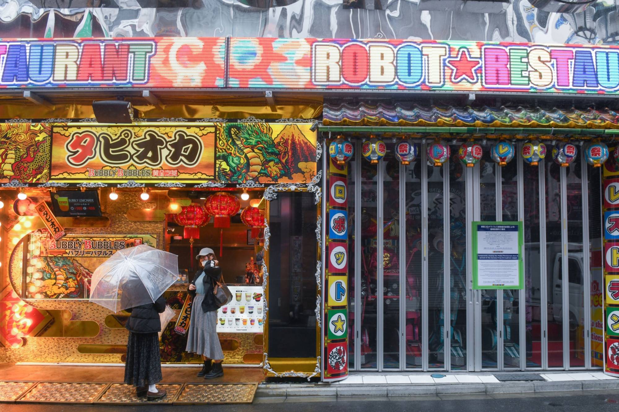 Customers stand in front of a bubble tea shop next to the Robot Restaurant, temporarily closed due to the coronavirus, in the Shinjuku district of Tokyo on April 1. | BLOOMBERG