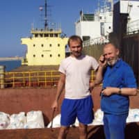 Boris Prokoshev (right), captain of the cargo vessel Rhosus, and boatswain Boris Musinchak pose next to a freight hold loaded with ammonium nitrate in the port of Beirut, Lebanon, in 2014. | REUTERS 