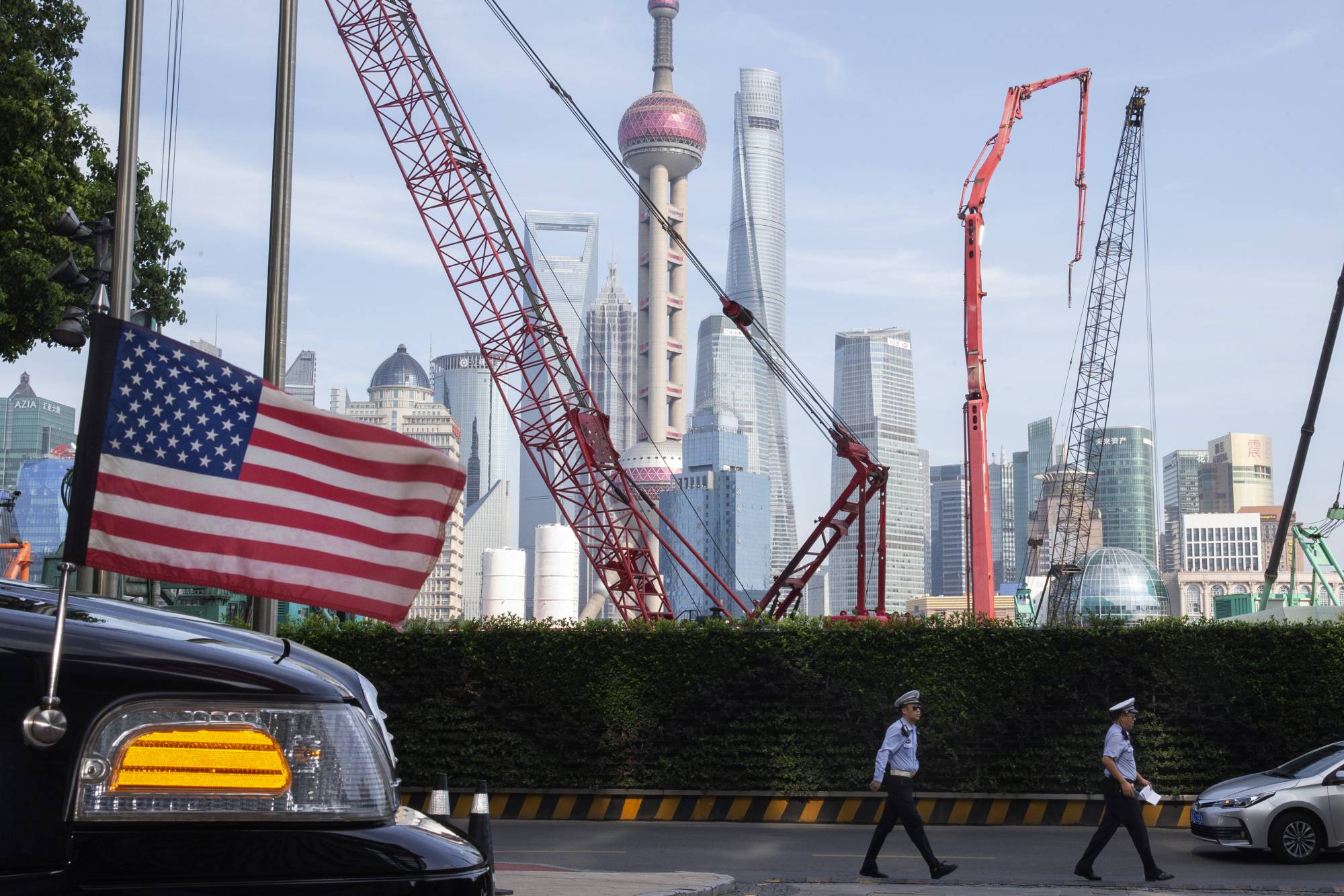 Chinese police walk by a U.S. Embassy car outside a hotel in Shanghai where officials from both sides were negotiating to end a tariff war on July 30, 2019. | AP