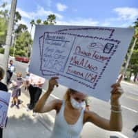 Protesters rally against changes to the United States Postal Services in Newport Beach, California, on Tuesday.  | THE ORANGE COUNTY REGISTER / VIA AP